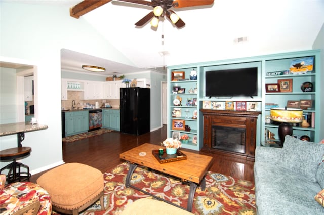 living area featuring lofted ceiling with beams, dark wood-style floors, ceiling fan, and a glass covered fireplace