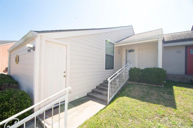 property entrance with roof with shingles and a yard