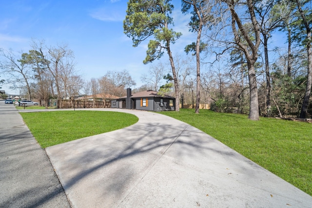 view of front of house with driveway, a front lawn, and a chimney