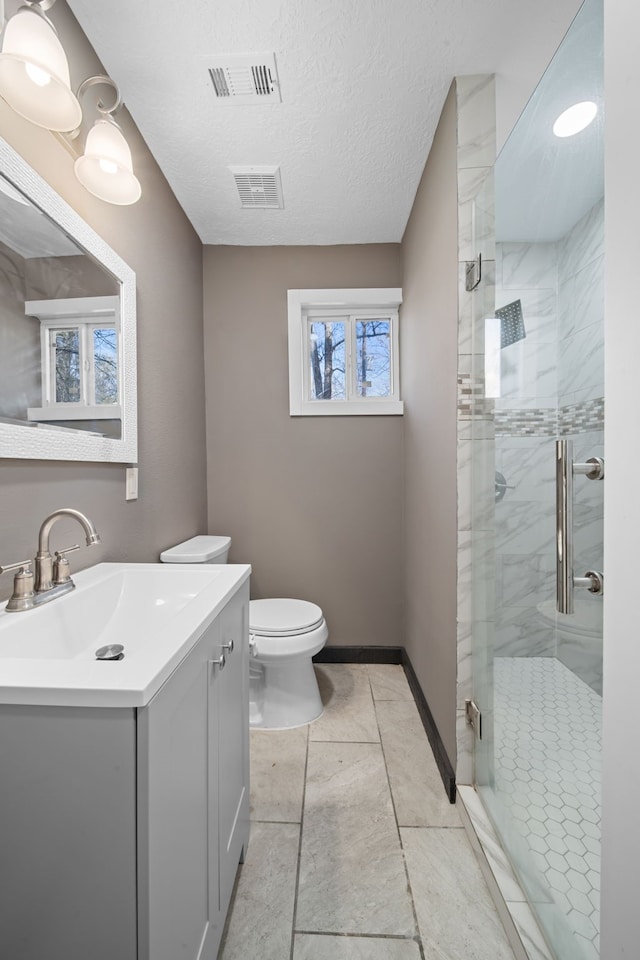 bathroom featuring toilet, vanity, visible vents, and a shower stall