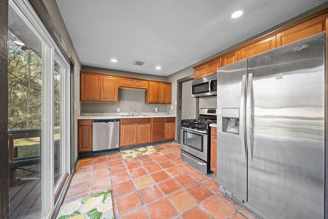 kitchen with brown cabinets, recessed lighting, light countertops, appliances with stainless steel finishes, and a sink