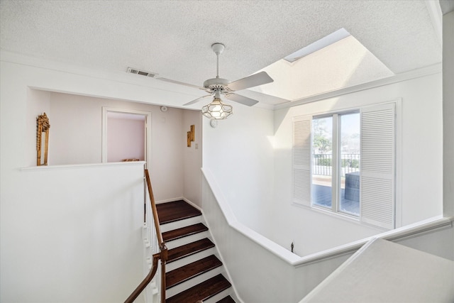 stairs with visible vents, a textured ceiling, and a ceiling fan