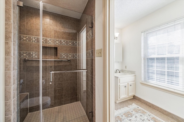 bathroom featuring tile patterned flooring, a shower stall, baseboards, vanity, and a textured ceiling