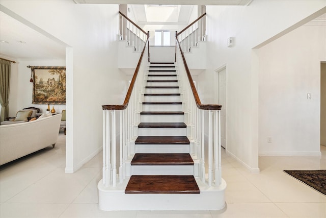 stairs featuring tile patterned flooring, baseboards, and a towering ceiling