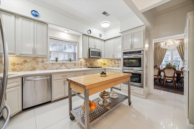 kitchen with light tile patterned floors, stainless steel appliances, decorative backsplash, and light countertops