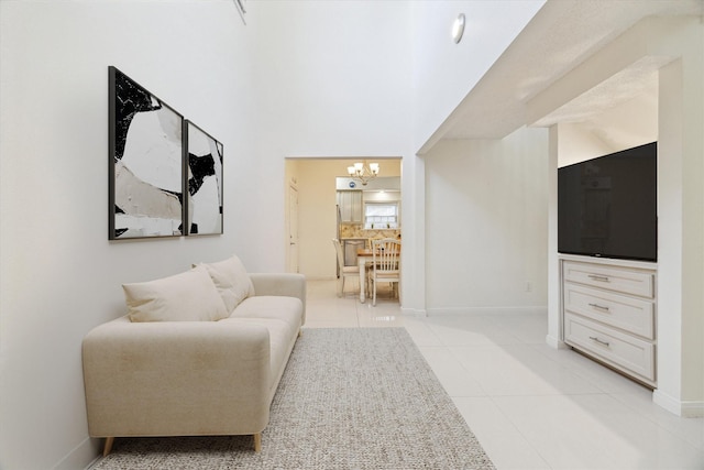 sitting room featuring light tile patterned floors, baseboards, a high ceiling, and a chandelier