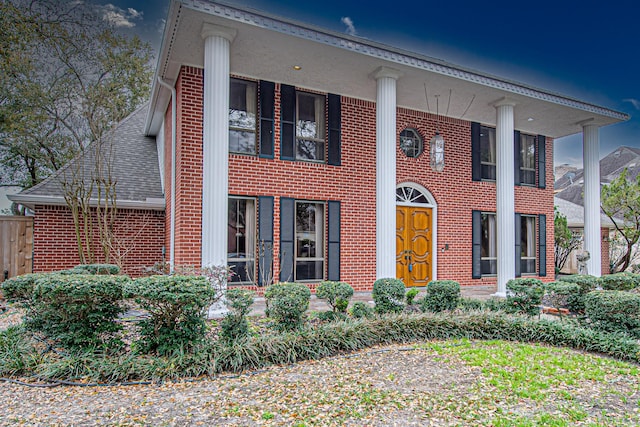 greek revival house with a shingled roof and brick siding