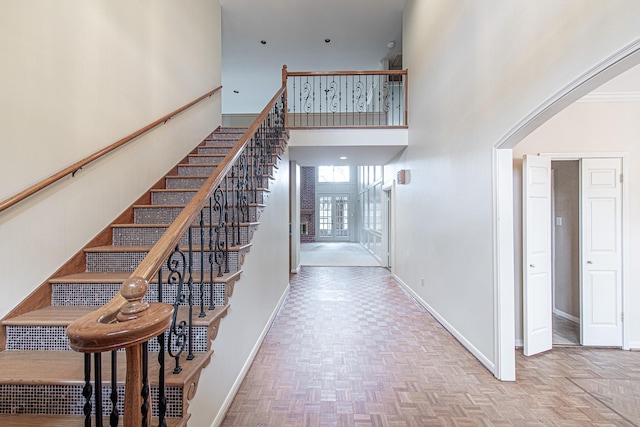 stairs with baseboards and a high ceiling