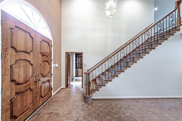 entrance foyer featuring stairway, a towering ceiling, and baseboards