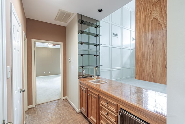 bar featuring a ceiling fan, baseboards, visible vents, and a sink