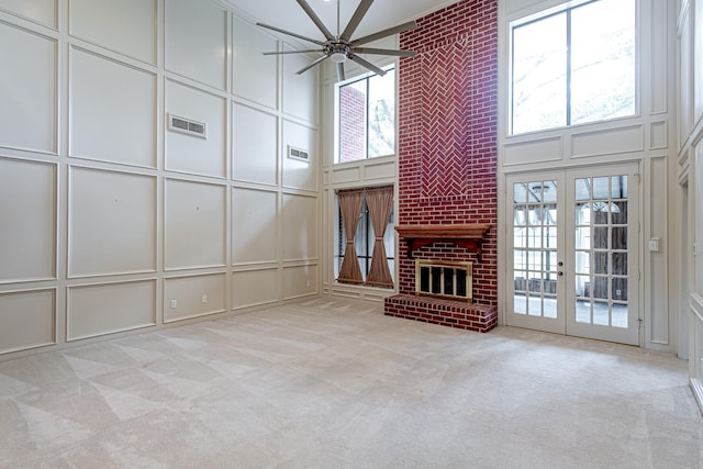 unfurnished living room featuring carpet floors, french doors, visible vents, a decorative wall, and a ceiling fan