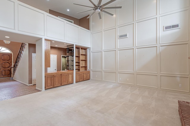 spare room with light carpet, a decorative wall, and visible vents