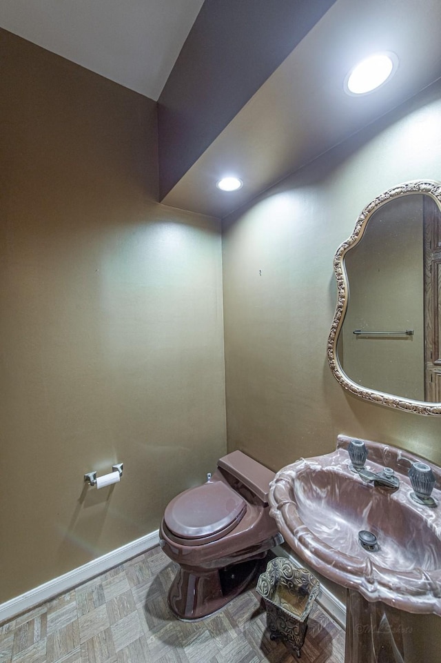 half bath with recessed lighting, baseboards, a sink, and toilet