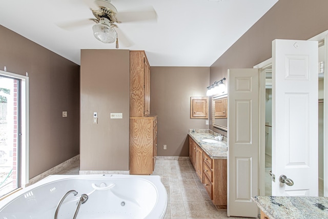 bathroom with baseboards, a ceiling fan, a tub with jets, tile patterned flooring, and vanity