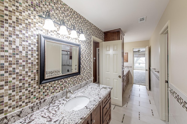 full bathroom with tile patterned flooring, visible vents, vanity, tile walls, and backsplash