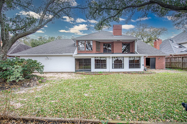 rear view of property featuring a balcony, brick siding, fence, a lawn, and a chimney