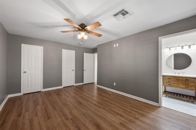 unfurnished bedroom with baseboards, visible vents, wood finished floors, and ensuite bathroom