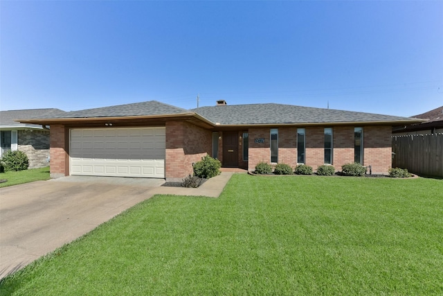 view of front of property featuring an attached garage, brick siding, a front lawn, and roof with shingles