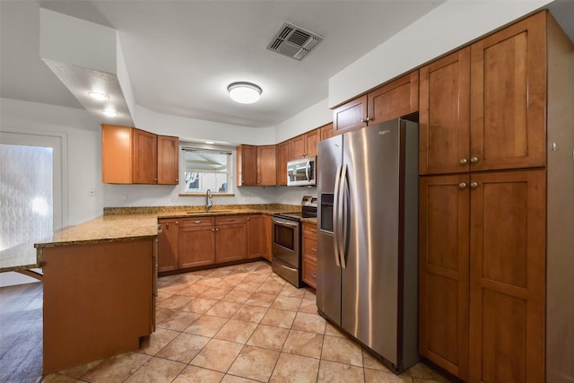 kitchen featuring visible vents, brown cabinetry, appliances with stainless steel finishes, a peninsula, and a sink