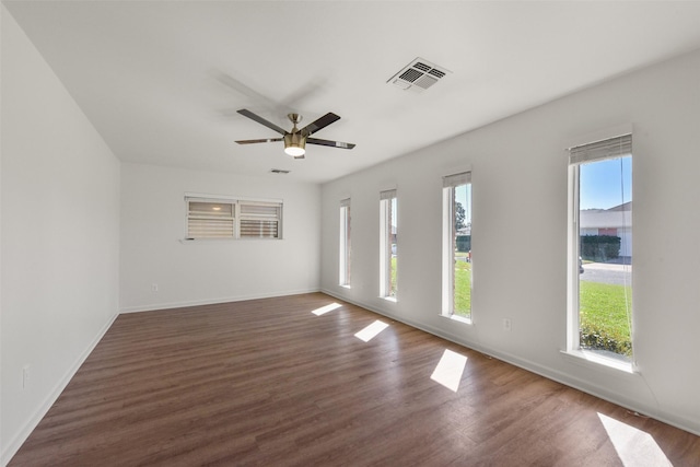 spare room featuring a wealth of natural light, dark wood-style flooring, visible vents, and baseboards