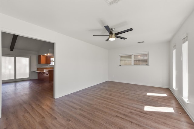 empty room featuring a wealth of natural light, visible vents, and wood finished floors