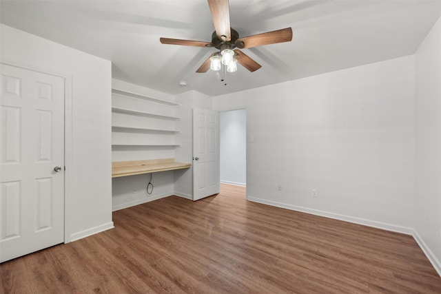 unfurnished bedroom featuring a ceiling fan, baseboards, wood finished floors, and built in study area