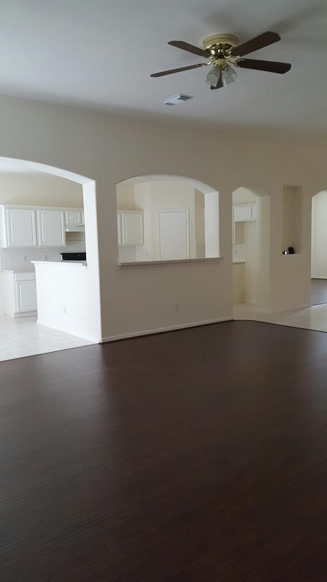 unfurnished living room featuring ceiling fan, visible vents, and wood finished floors