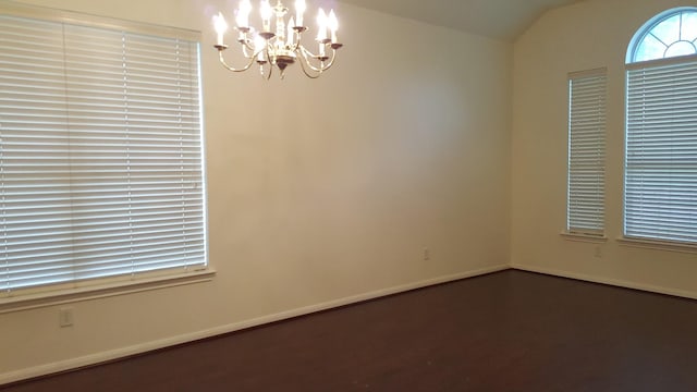 spare room with lofted ceiling, baseboards, and an inviting chandelier