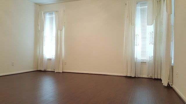 empty room with dark wood-type flooring and baseboards