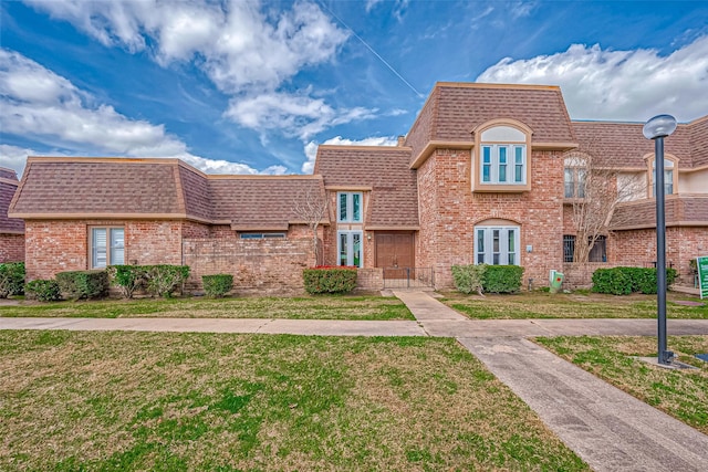 view of front of property with a shingled roof, mansard roof, a gate, a front yard, and brick siding