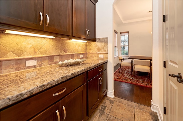 kitchen featuring tasteful backsplash, light stone counters, and ornamental molding