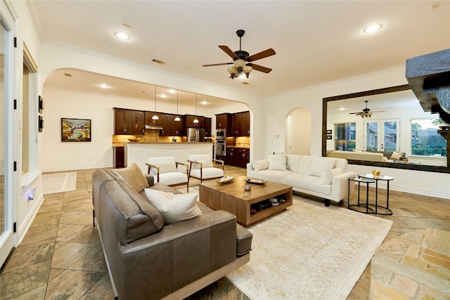 living room featuring visible vents, stone tile floors, recessed lighting, arched walkways, and crown molding