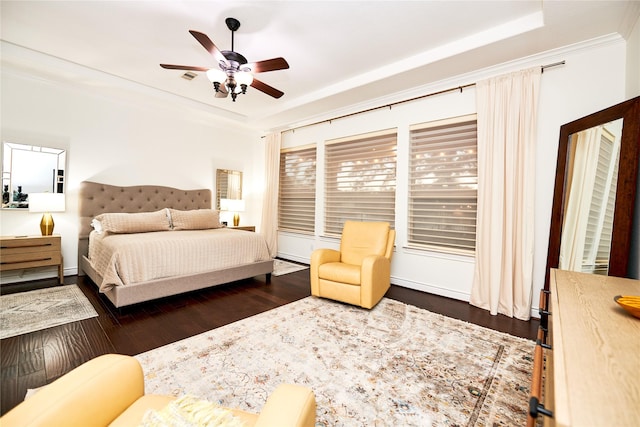 bedroom featuring dark wood finished floors, visible vents, a raised ceiling, and crown molding