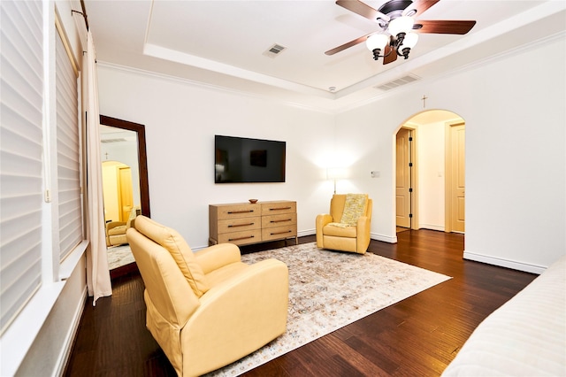 living room featuring visible vents, a ceiling fan, a tray ceiling, dark wood-style floors, and arched walkways