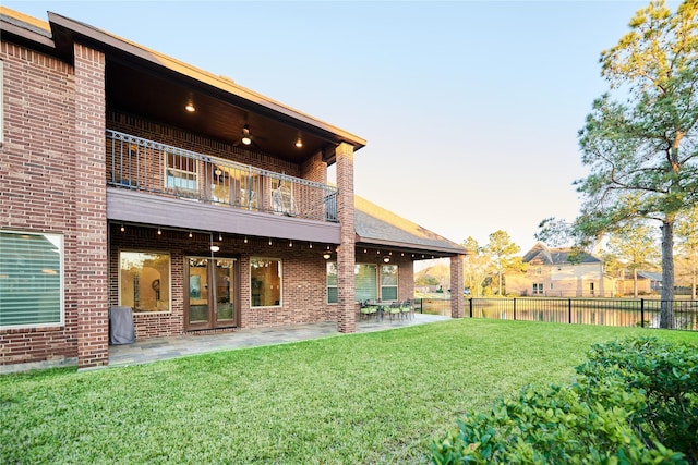 back of house with brick siding, a lawn, and fence