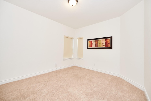 unfurnished room with baseboards and light carpet