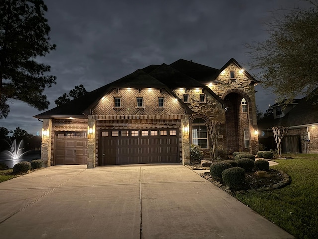 view of front facade featuring an attached garage, brick siding, stone siding, and driveway