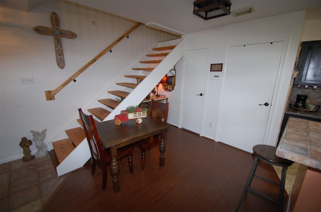 dining space with visible vents, stairway, and wood finished floors