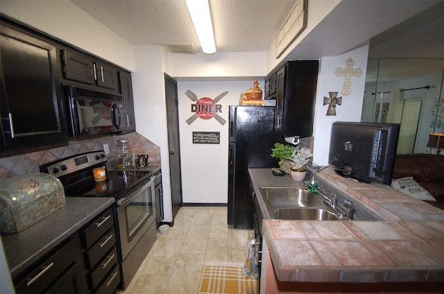 kitchen with a sink, visible vents, dark cabinetry, decorative backsplash, and black appliances