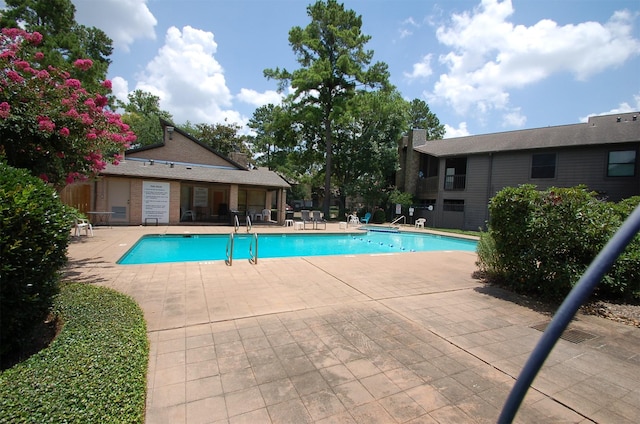 pool with a patio area and fence