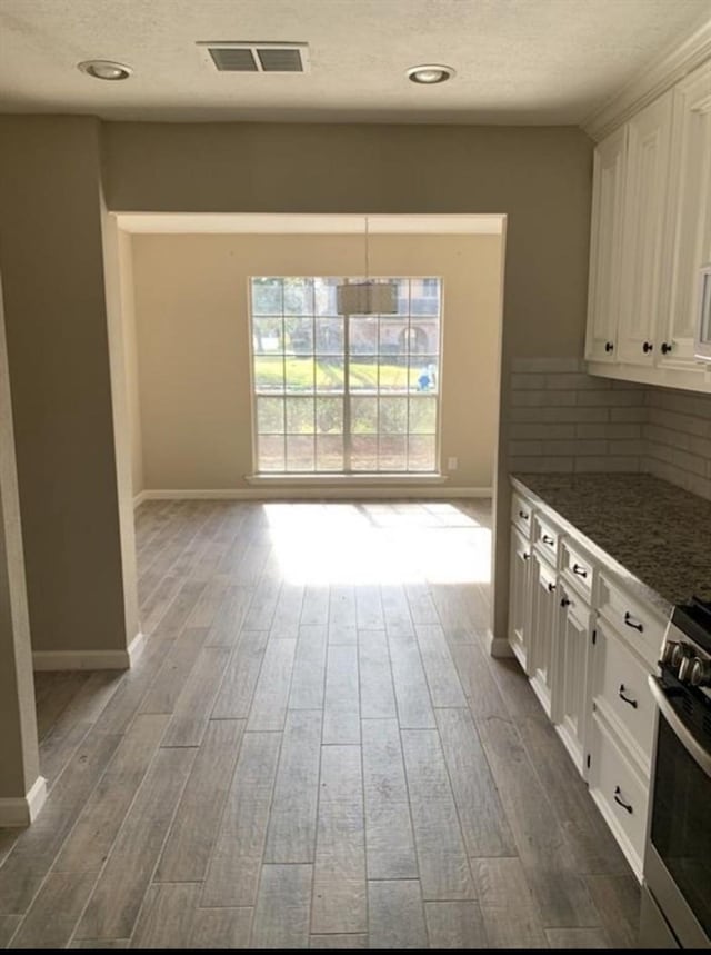 kitchen featuring gas range, dark wood finished floors, visible vents, and white cabinets