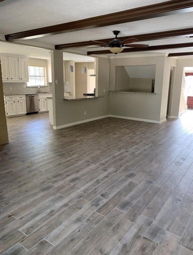 unfurnished living room featuring beam ceiling, ceiling fan, baseboards, and wood finished floors