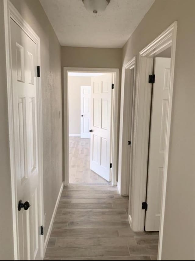 hallway with baseboards and wood finished floors