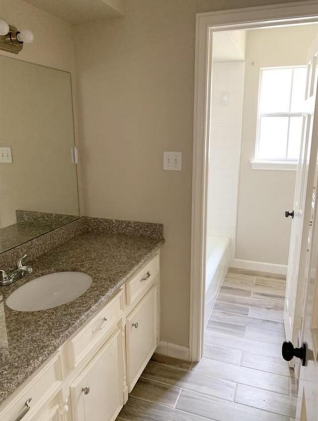 full bathroom with wood tiled floor, baseboards, and vanity