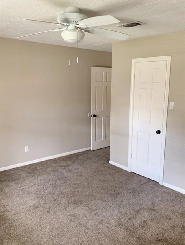 carpeted empty room with a ceiling fan, baseboards, visible vents, and a textured ceiling