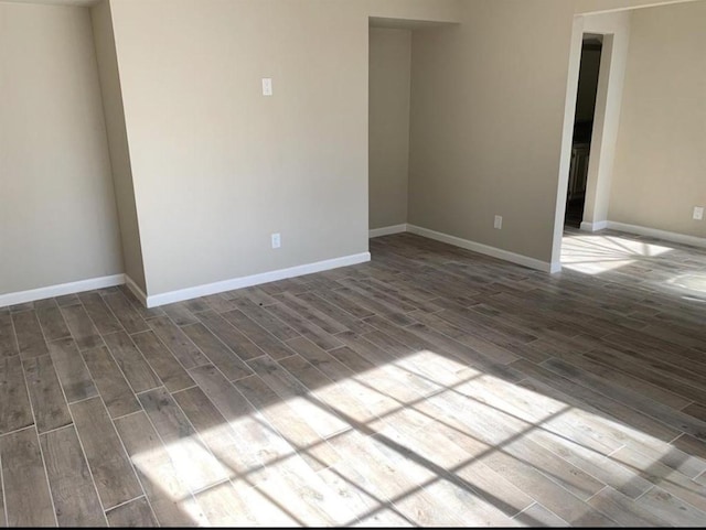 unfurnished room featuring dark wood-type flooring and baseboards