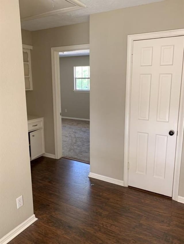 interior space featuring dark wood-style floors, attic access, and baseboards