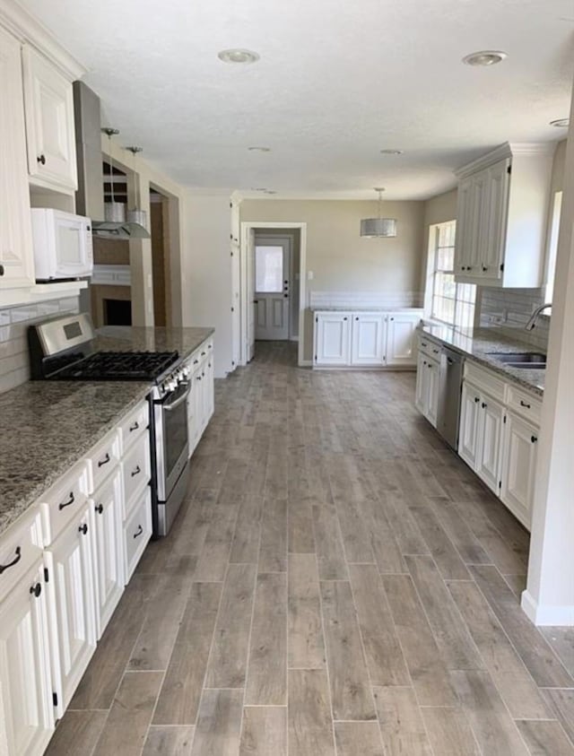 kitchen with light wood finished floors, backsplash, stainless steel appliances, and a sink