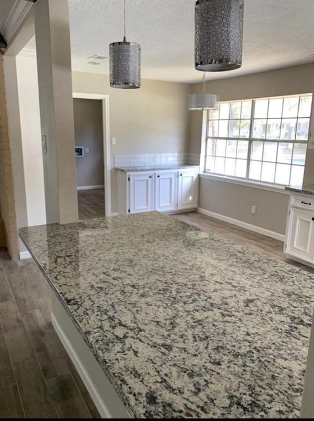 unfurnished dining area featuring a textured ceiling, baseboards, and wood finished floors