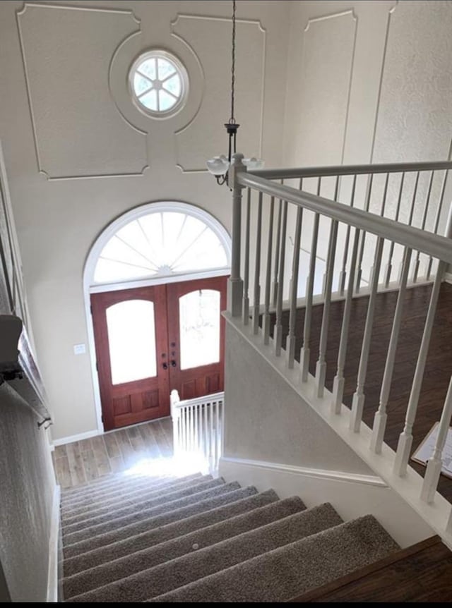 entrance foyer featuring a notable chandelier, a high ceiling, stairway, and wood finished floors